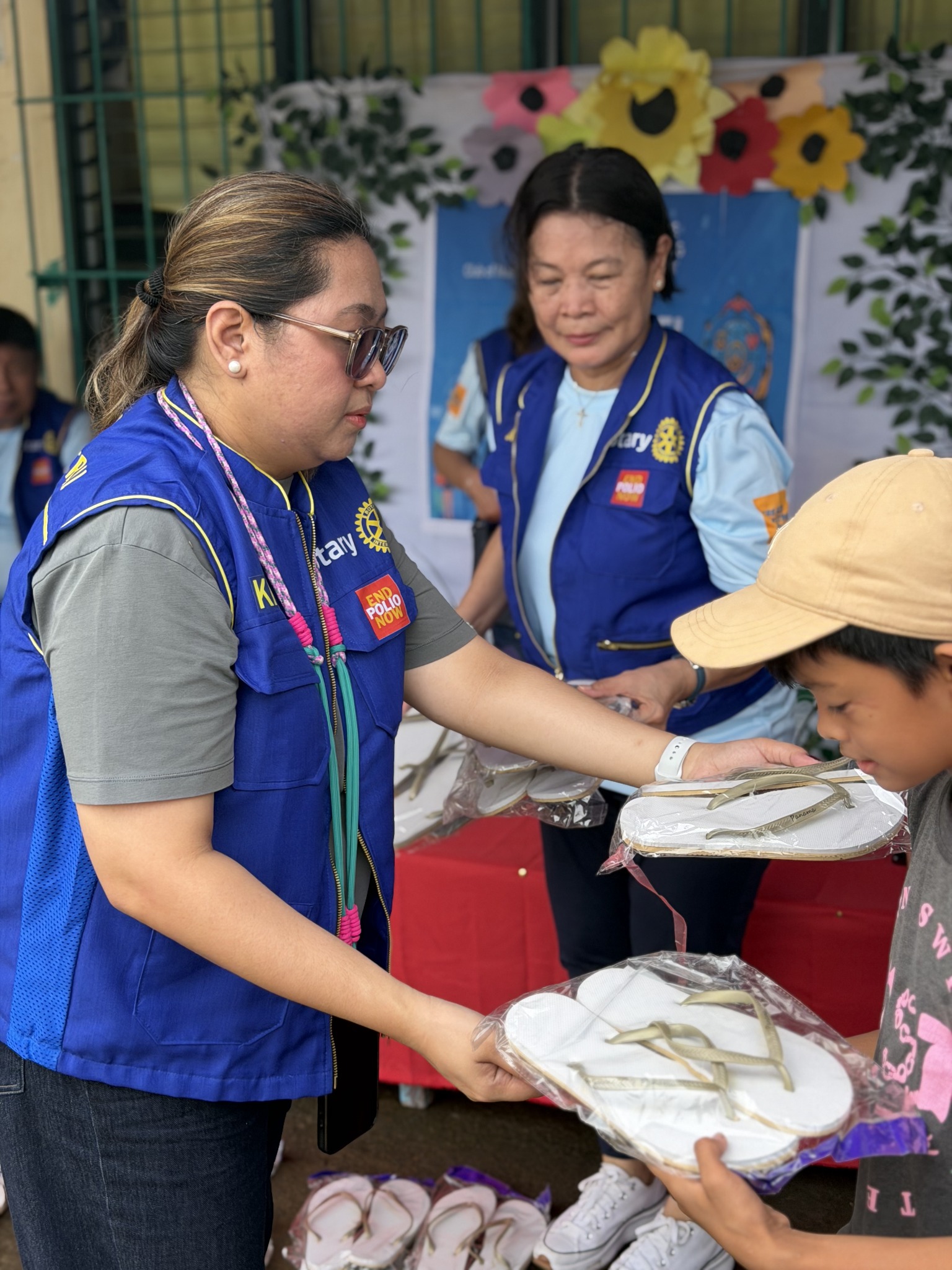 Rotary Club of Mandaluyong Central volunteer giving slippers to a child
